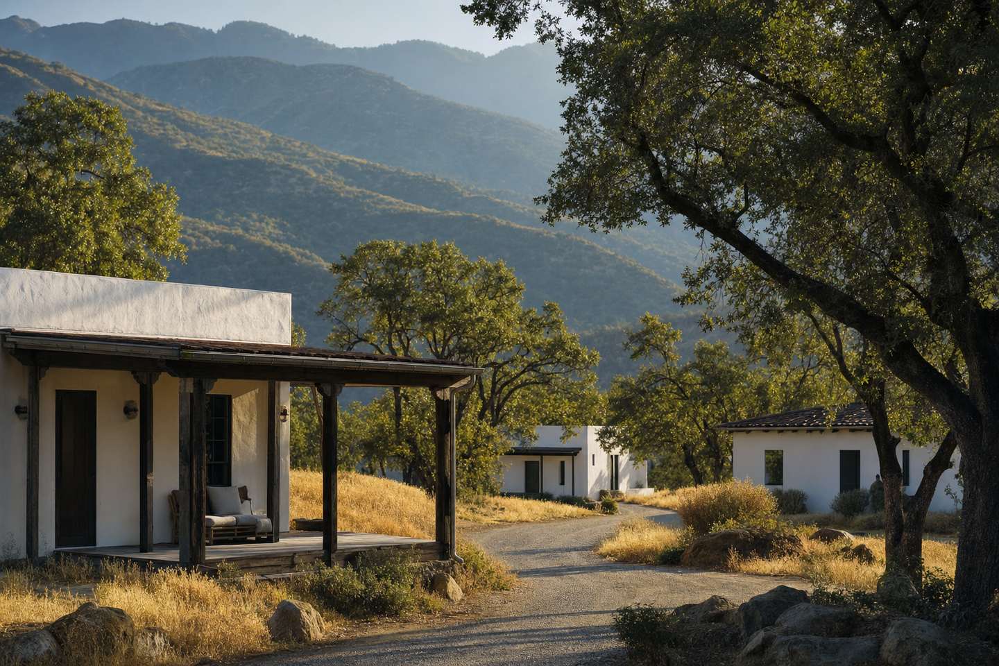 Low white-walled buildings with shaded porches scattered across oak-studded foothills near Keene