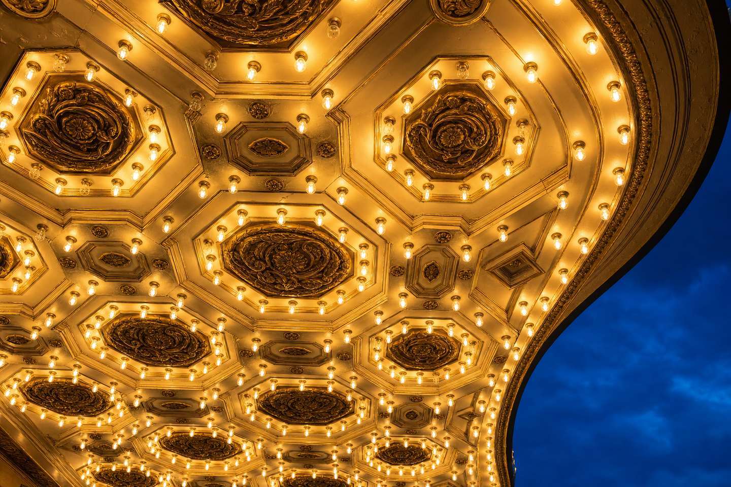 A restored downtown theater marquee lit up at dusk on a historic city street