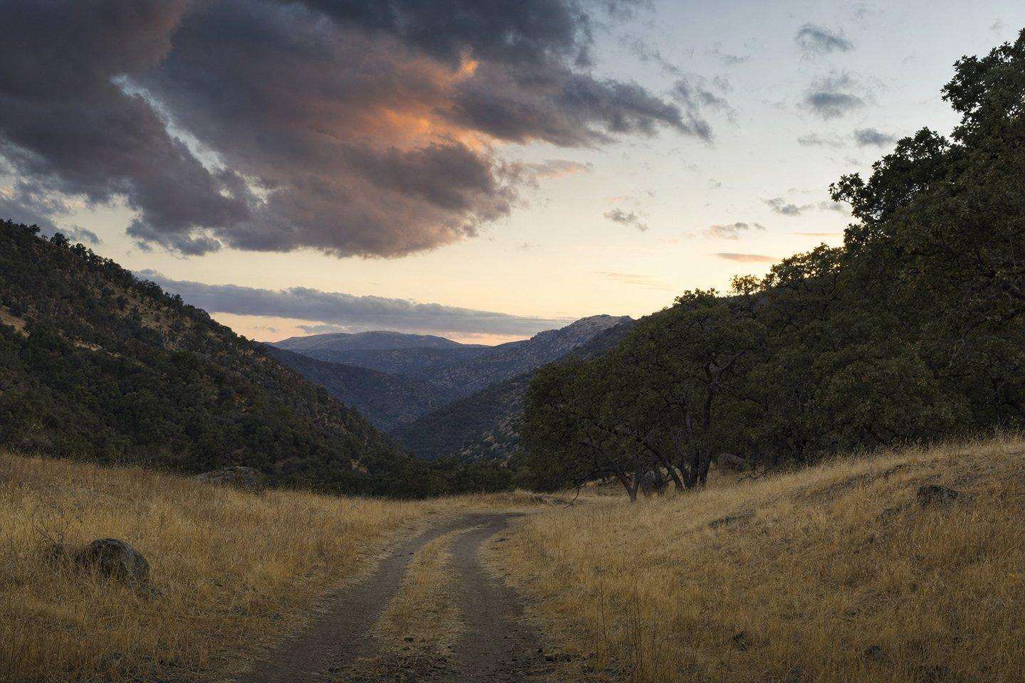 A remote, empty golden-grass mountain valley in the Sierra Nevada foothills at dusk